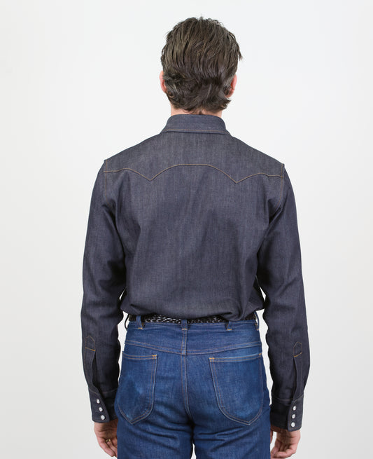 Man wearing a dark denim shirt and jeans on a white background
