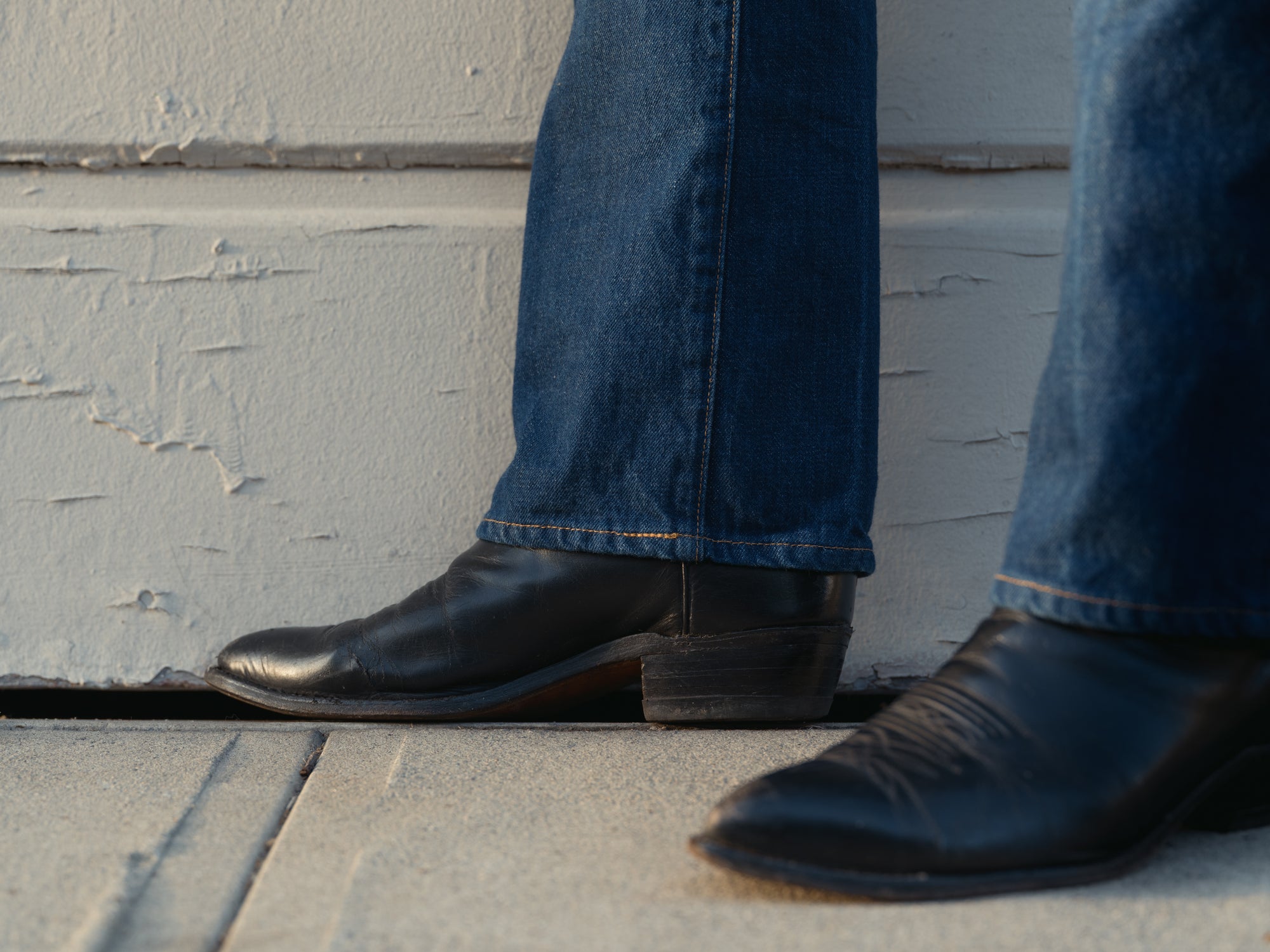 Cowboy jean and denim shirt worn against a concrete wall in hard afternoon light