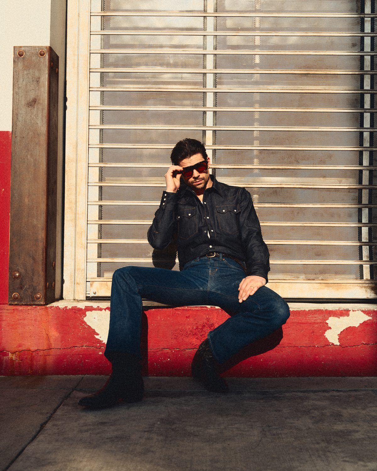 Seated on the red curb in full denim
